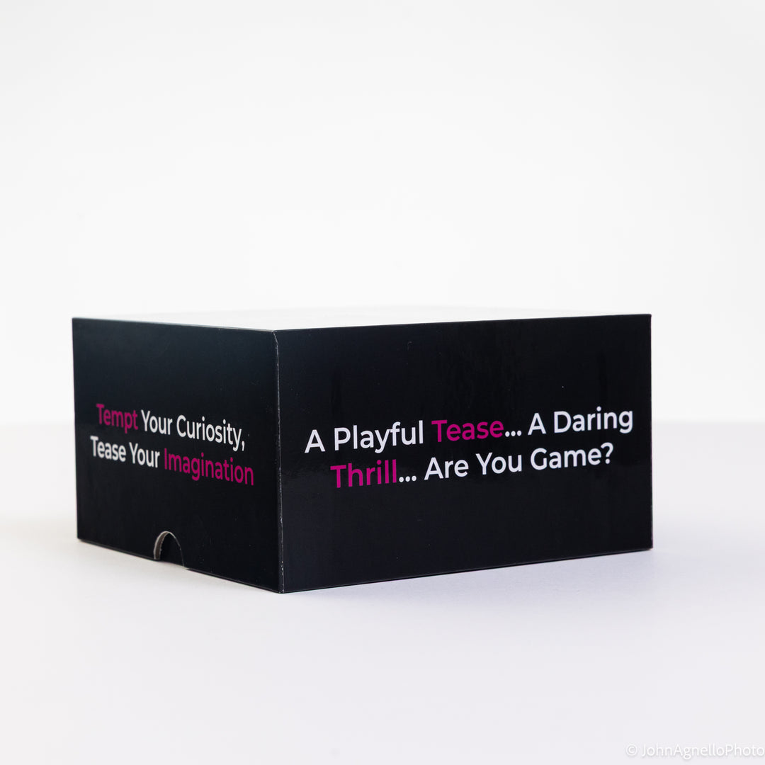 A black rectangular product box with white and pink text, photographed on a clean white studio background. The visible text reads, &